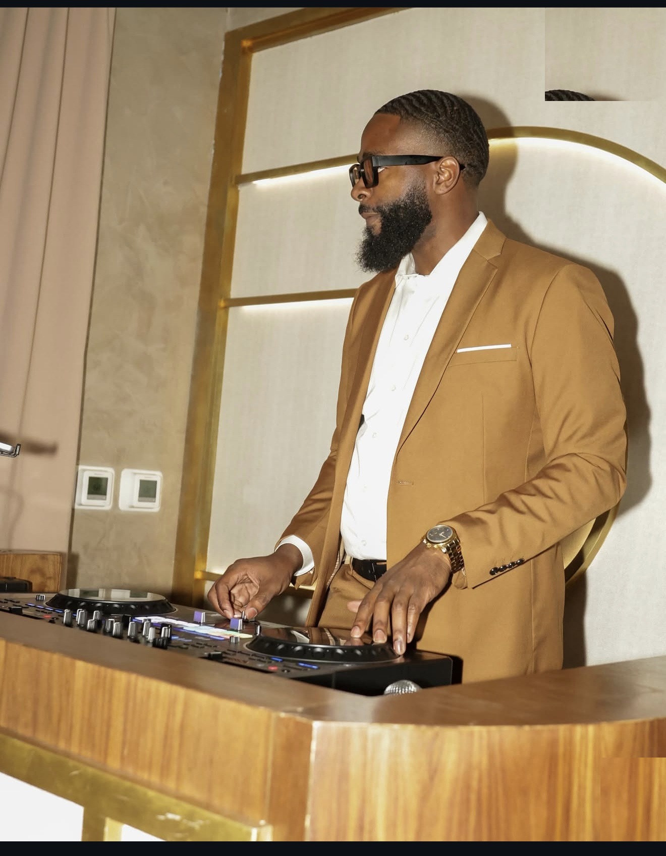 DJ FLYY performing in a tan suit at an event