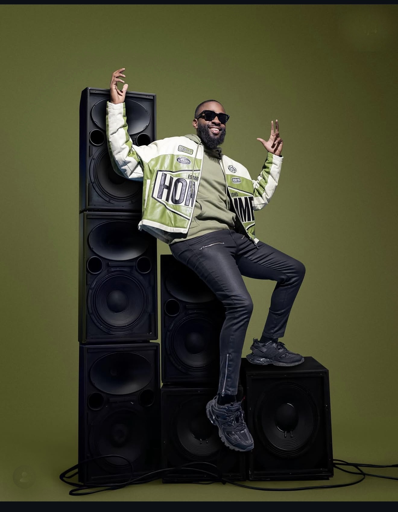 DJ FLYY posing with a speaker stack at an event