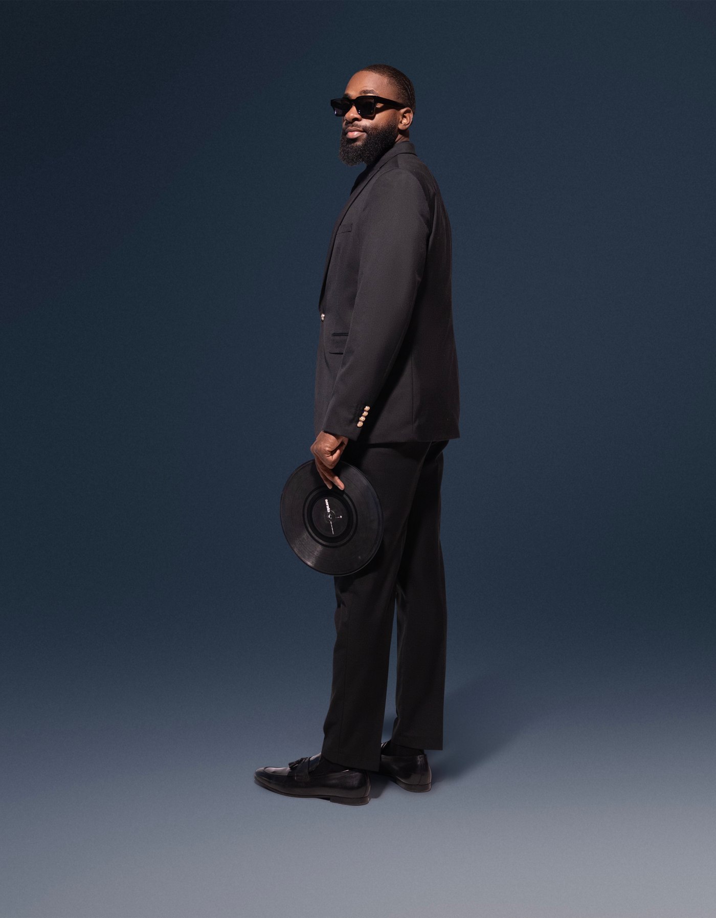 DJ FLYY holding a vinyl record, studio portrait